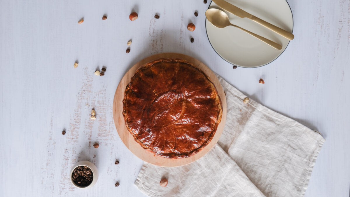 une galette des rois est posée sur une table à côté d'un couteau et d'une fourchette.