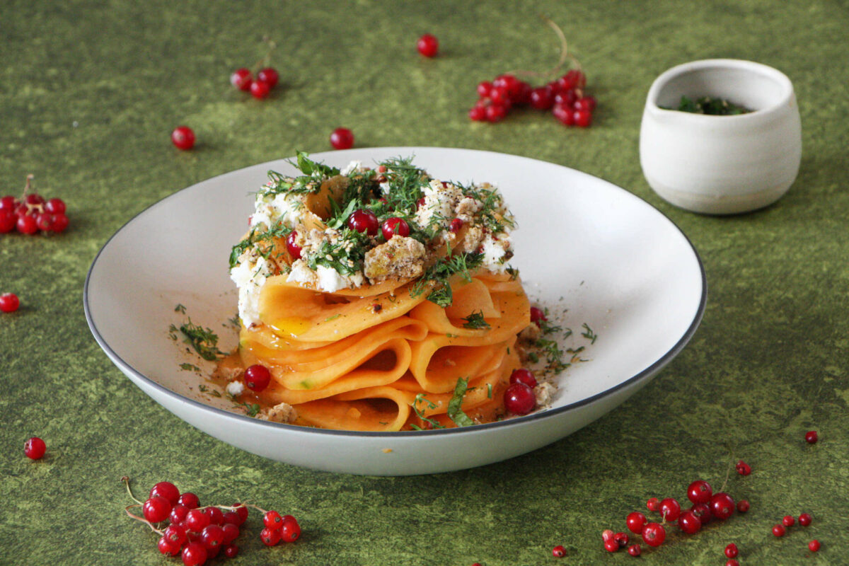 un bol de pâtes aux fruits rouges et carpaccio de melon dessus.