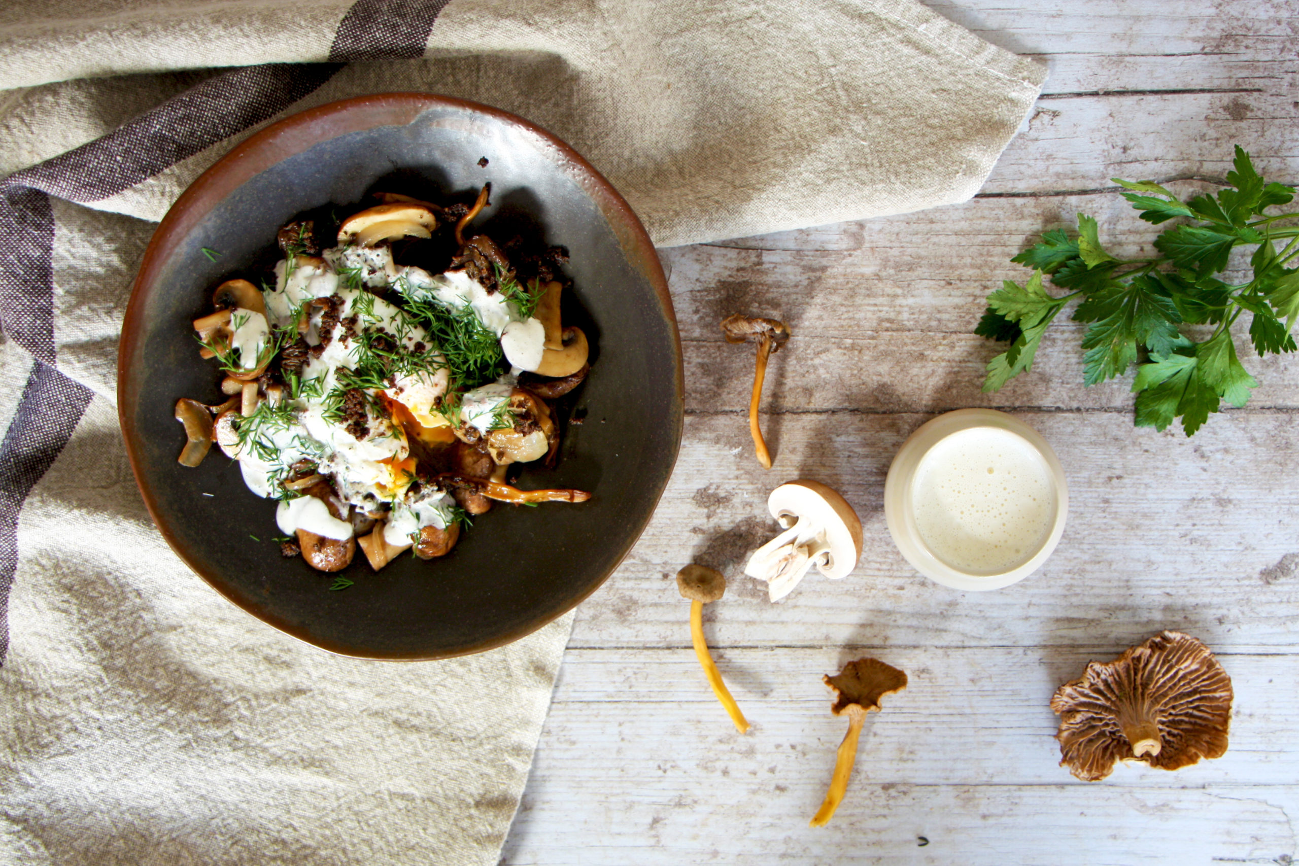 un bol de champignons et d'herbes sur une table en bois.