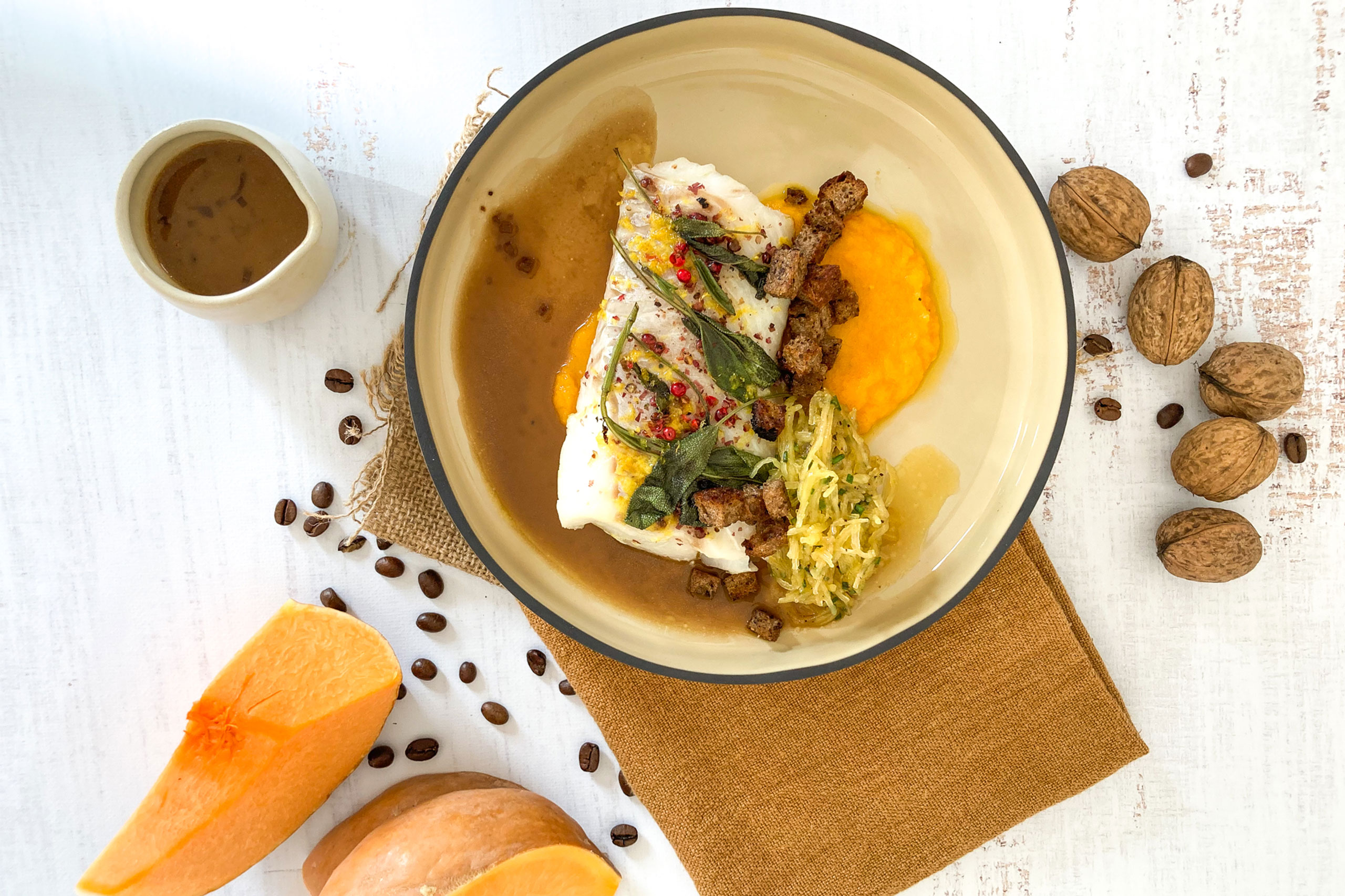 un bol de poisson avec une sauce et des noix sur une table en bois, servi avec du beurre blanc.