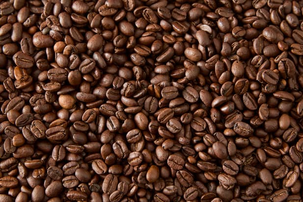 Une vue rapprochée de nombreux grains de café brun torréfiés.